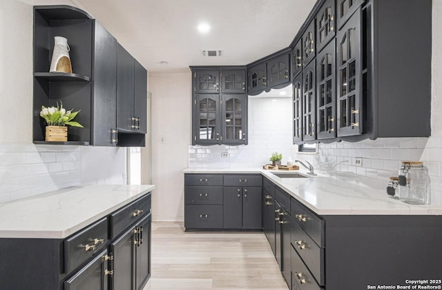 kitchen featuring light hardwood / wood-style floors, light stone counters, sink, and tasteful backsplash