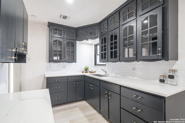 kitchen with decorative backsplash, light stone counters, and sink