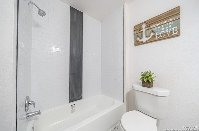 bathroom with toilet and tiled shower / bath