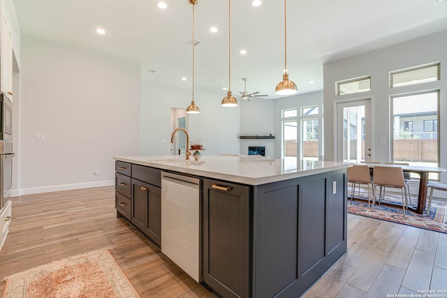 kitchen featuring ceiling fan, sink, stainless steel appliances, pendant lighting, and a kitchen island with sink