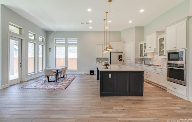 kitchen with decorative backsplash, white cabinets, decorative light fixtures, and appliances with stainless steel finishes