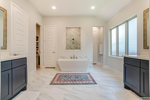 bathroom featuring vanity, a tub to relax in, and vaulted ceiling