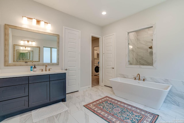 bathroom with washer / dryer, vanity, and a tub