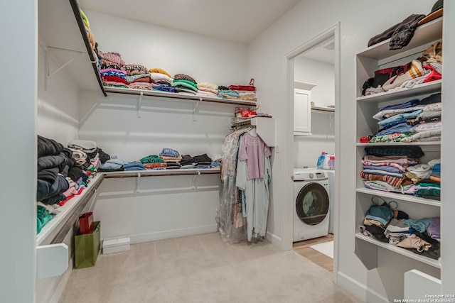 spacious closet featuring light colored carpet and washer / clothes dryer