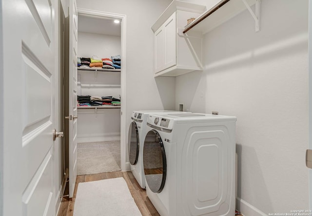 laundry room featuring cabinets, separate washer and dryer, and light hardwood / wood-style flooring