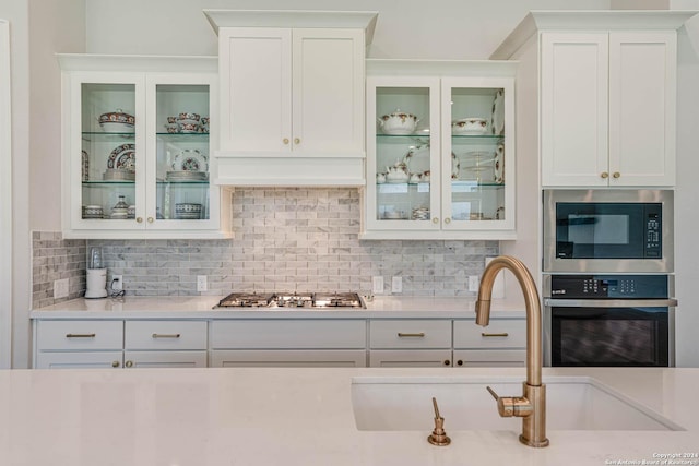 kitchen featuring white cabinets, decorative backsplash, stainless steel appliances, and sink