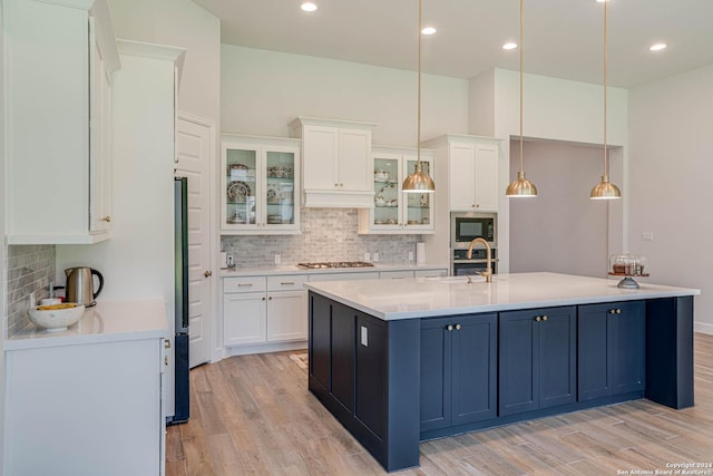 kitchen with stainless steel appliances, blue cabinets, pendant lighting, a center island with sink, and white cabinets