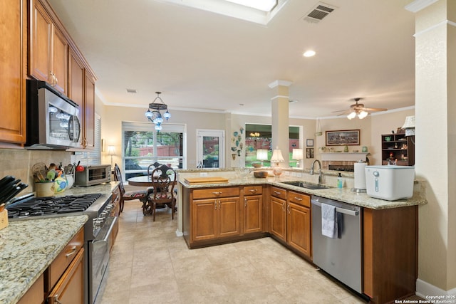 kitchen featuring kitchen peninsula, appliances with stainless steel finishes, light stone countertops, ceiling fan, and sink