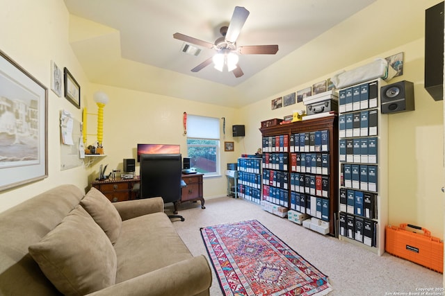 interior space with a raised ceiling, light carpet, and ceiling fan