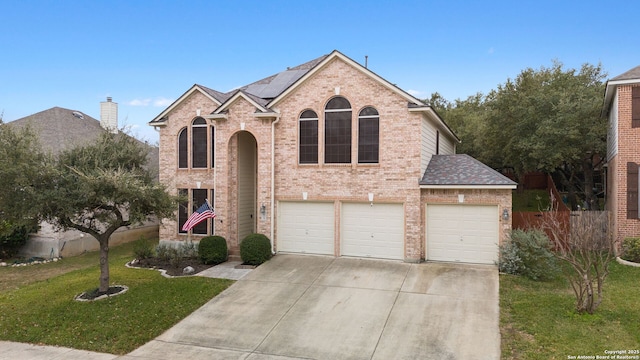 view of front of property featuring solar panels, a garage, and a front lawn