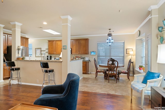 kitchen featuring light stone counters, ornamental molding, kitchen peninsula, a kitchen bar, and hardwood / wood-style flooring