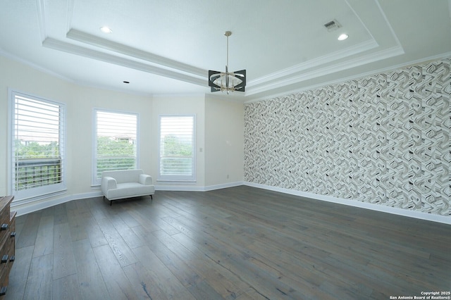 unfurnished room featuring a raised ceiling, dark hardwood / wood-style floors, an inviting chandelier, and crown molding