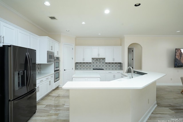 kitchen with white cabinets, a large island with sink, backsplash, and stainless steel appliances