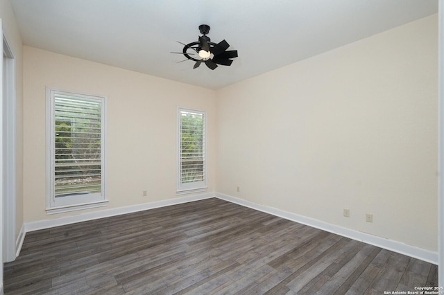 spare room with ceiling fan, a healthy amount of sunlight, and dark wood-type flooring