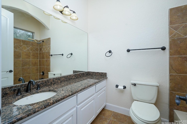 bathroom featuring toilet, vanity, tiled shower, and tile patterned floors