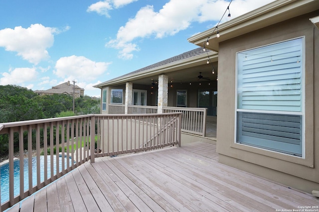 wooden deck with ceiling fan and a swimming pool