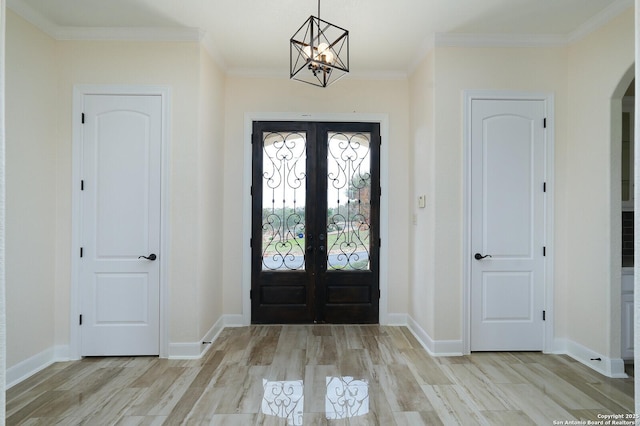 entryway with french doors, light wood-type flooring, an inviting chandelier, and crown molding