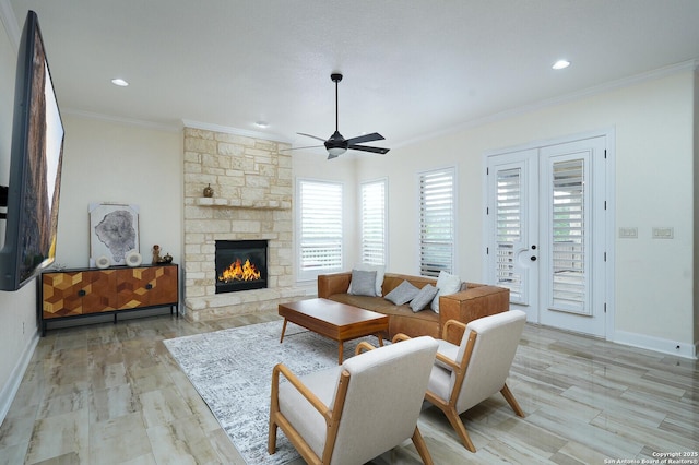 living room featuring a fireplace, light hardwood / wood-style flooring, ceiling fan, and crown molding