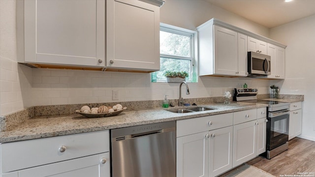 kitchen with white cabinets, stainless steel appliances, light hardwood / wood-style floors, and sink