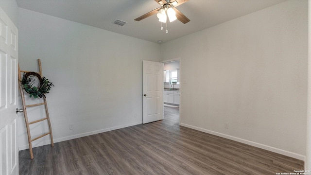 empty room with ceiling fan and dark wood-type flooring