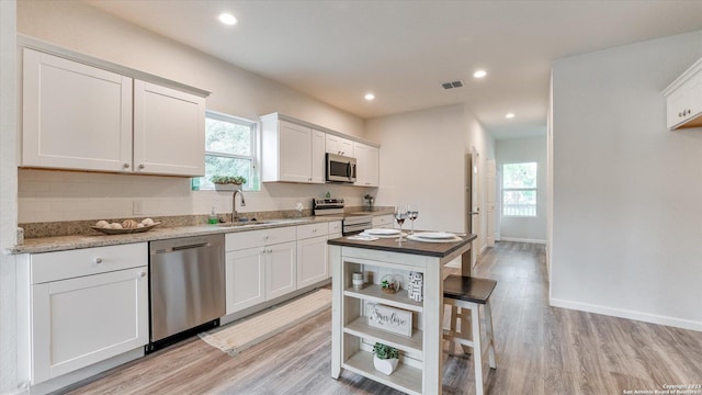 kitchen featuring sink, light hardwood / wood-style flooring, a healthy amount of sunlight, white cabinetry, and stainless steel appliances