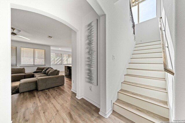 stairs with wood-type flooring and ceiling fan