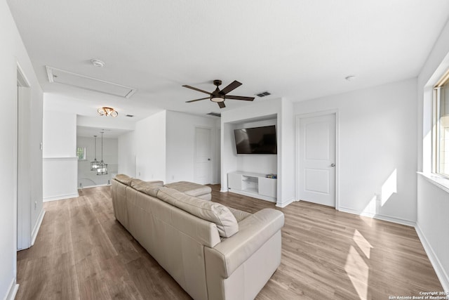 living room featuring ceiling fan with notable chandelier and light hardwood / wood-style flooring