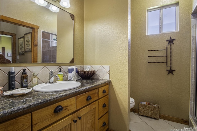 bathroom with tasteful backsplash, vanity, tile patterned flooring, and toilet