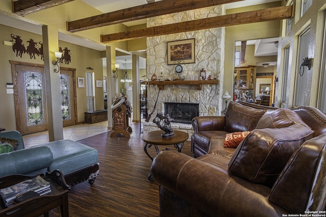 living room with hardwood / wood-style flooring, a stone fireplace, and a chandelier