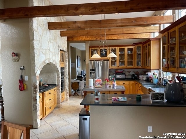 kitchen with light tile patterned flooring, sink, stainless steel fridge, kitchen peninsula, and pendant lighting