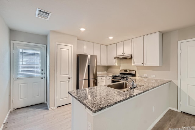 kitchen featuring white cabinets, kitchen peninsula, stainless steel appliances, and dark stone counters