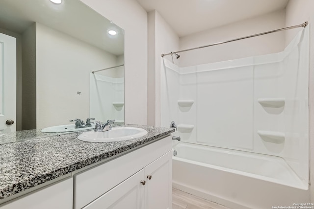 bathroom with wood-type flooring, vanity, and tub / shower combination