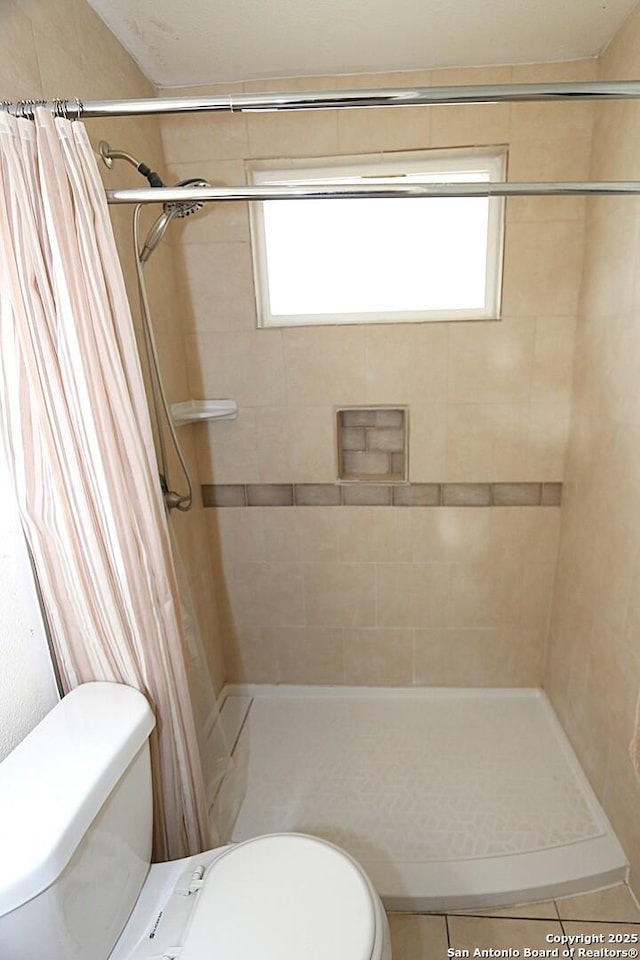 bathroom with tile patterned floors, a shower with curtain, toilet, and a wealth of natural light