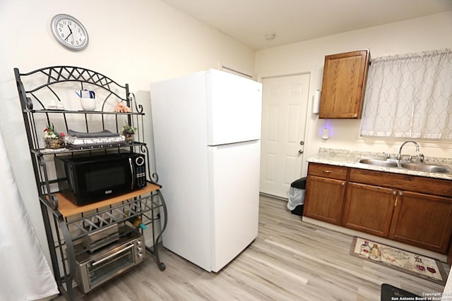 kitchen featuring sink, light wood-type flooring, and white refrigerator