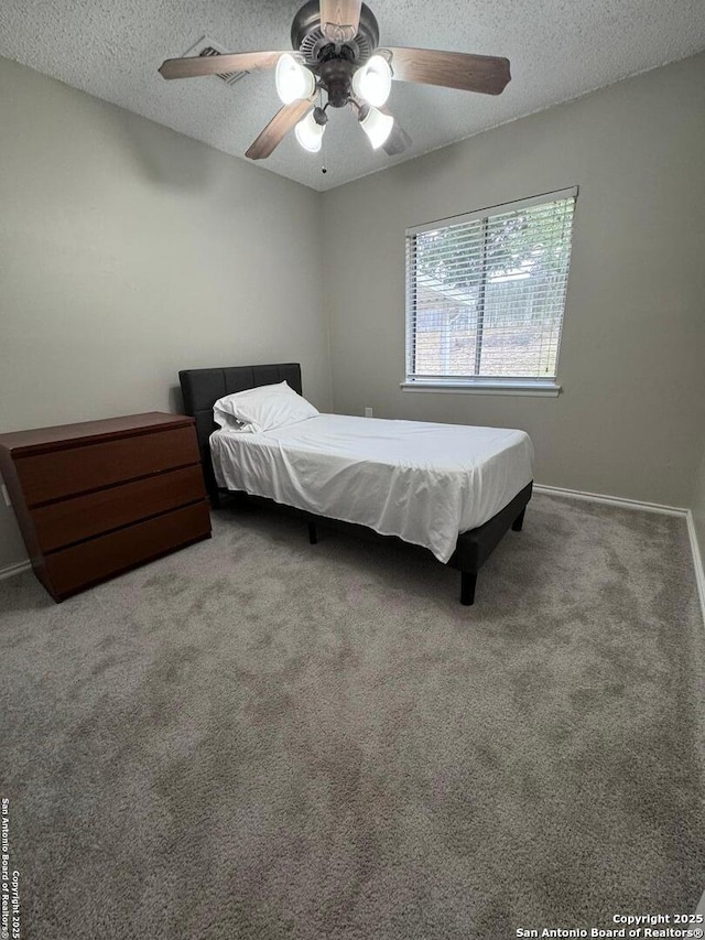 carpeted bedroom with ceiling fan and a textured ceiling