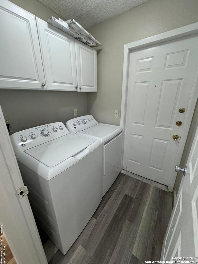 clothes washing area with cabinets, separate washer and dryer, a textured ceiling, and dark wood-type flooring