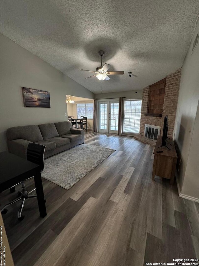 living room featuring a textured ceiling, lofted ceiling, dark hardwood / wood-style flooring, a brick fireplace, and ceiling fan