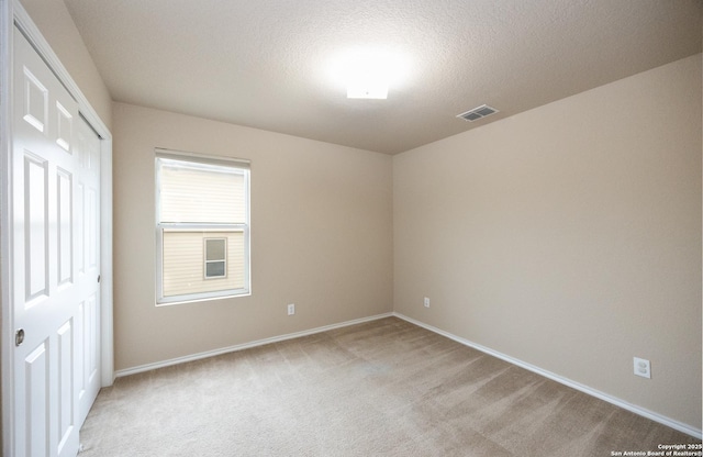 carpeted spare room featuring a textured ceiling