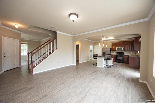 unfurnished living room with sink, ornamental molding, and light wood-type flooring