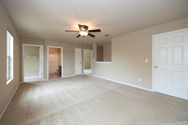 unfurnished bedroom with connected bathroom, light colored carpet, and ceiling fan