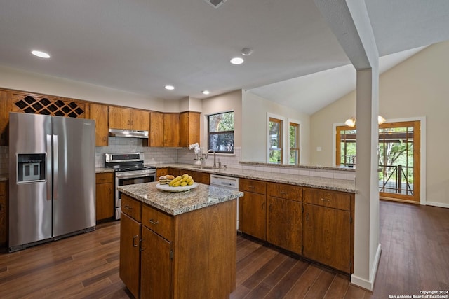 kitchen with stainless steel appliances, vaulted ceiling, sink, a kitchen island, and plenty of natural light