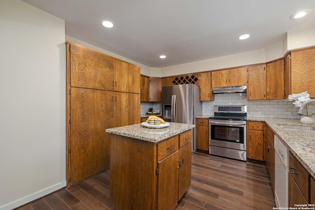 kitchen with dark hardwood / wood-style flooring, tasteful backsplash, stainless steel appliances, sink, and a center island