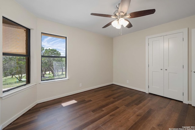 unfurnished bedroom with ceiling fan, dark wood-type flooring, and a closet