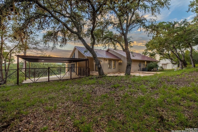 back house at dusk featuring a carport