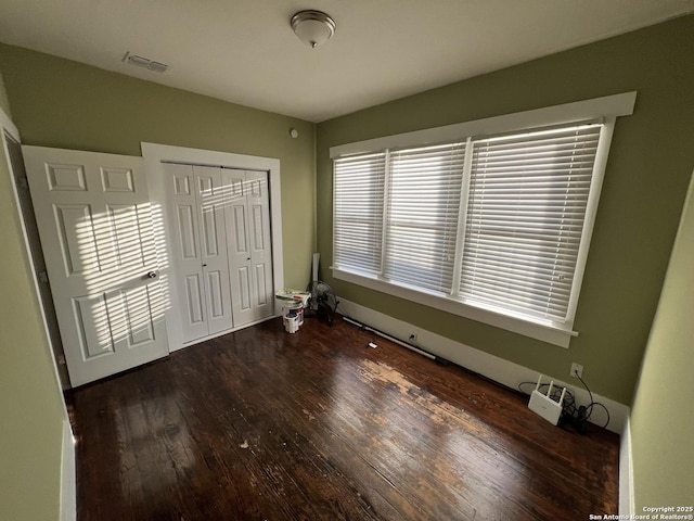 unfurnished bedroom featuring dark hardwood / wood-style flooring and a closet