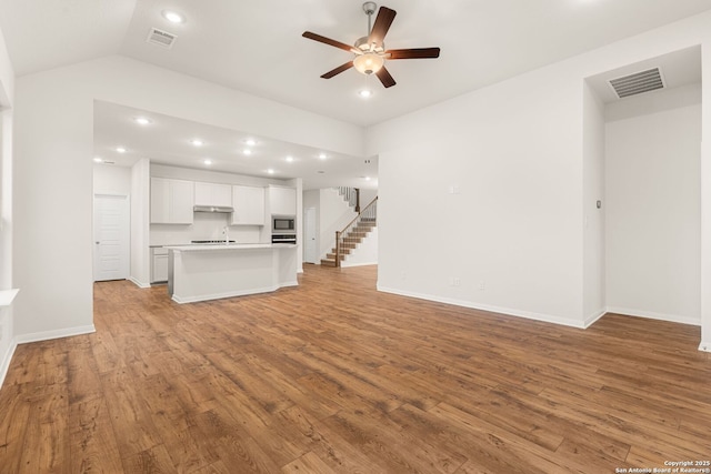 unfurnished living room with ceiling fan, lofted ceiling, and light wood-type flooring