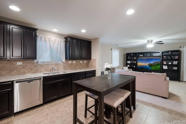 kitchen with ceiling fan, dishwasher, sink, tasteful backsplash, and light stone counters