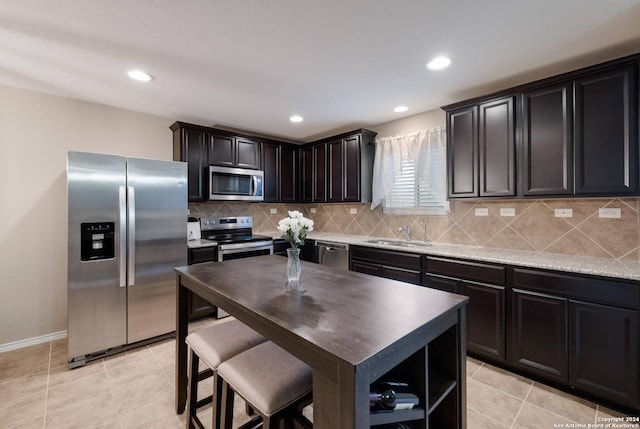 kitchen with sink, stainless steel appliances, tasteful backsplash, light stone counters, and light tile patterned flooring