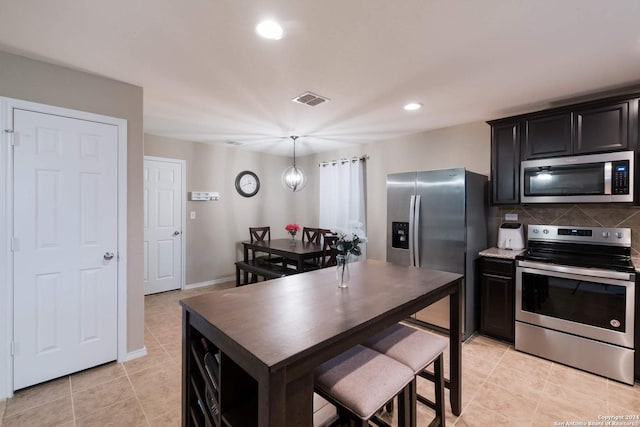 kitchen featuring appliances with stainless steel finishes, tasteful backsplash, light tile patterned floors, pendant lighting, and an inviting chandelier