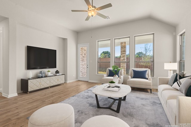 living room featuring ceiling fan, vaulted ceiling, and light hardwood / wood-style flooring